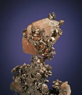 Calcite, silver and copper, South Hecla Mine, Houghton County, Michigan. A unique specimen of copper-included calcite perched on silver crystals. Donor: W. Weir. Specimen 7 cm tall. Photo by G. Robinson. (DM 168)